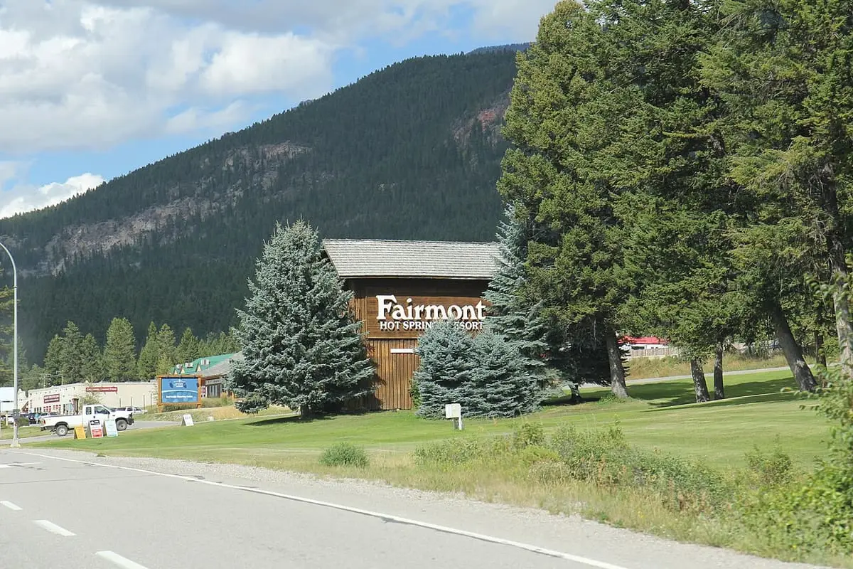 Fairmont Hot Springs Resort entrance sign on a lawn with spruce trees and forested hills