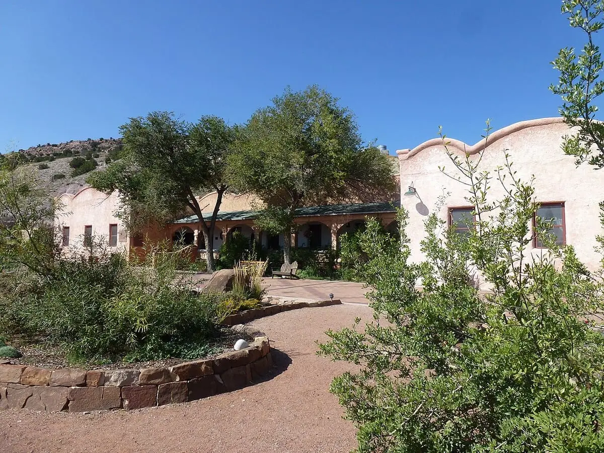 Adobe buildings and garden paths under a blue sky at Ojo Caliente Mineral Springs