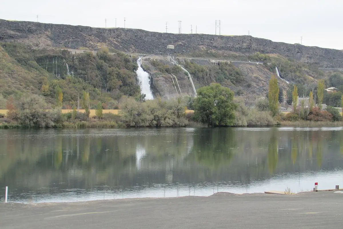 White spring cascades falling from the canyon wall across the calm Snake River in the Hagerman Valley