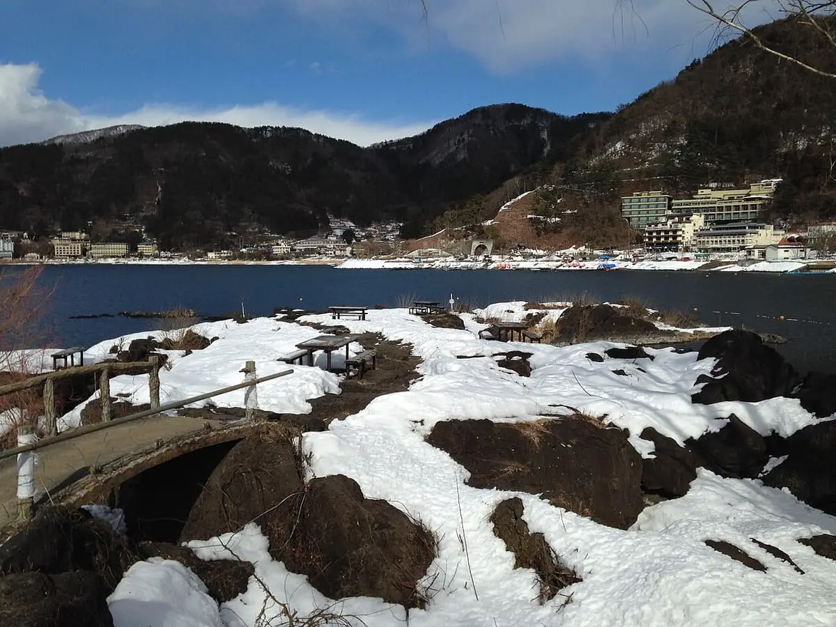 Snow covered lava rocks of Tatamiiwa on the Kawaguchiko shore with lakeside hotels across the water