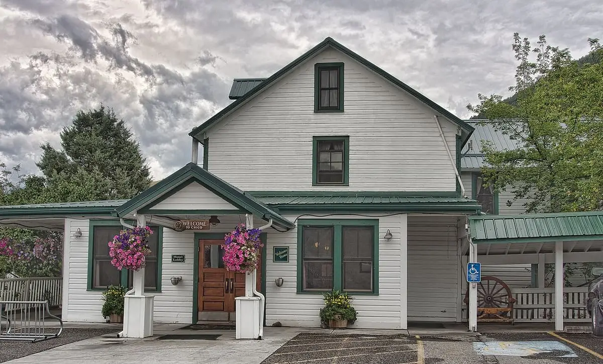 White clapboard main lodge at Chico Hot Springs with green trim and hanging flower baskets