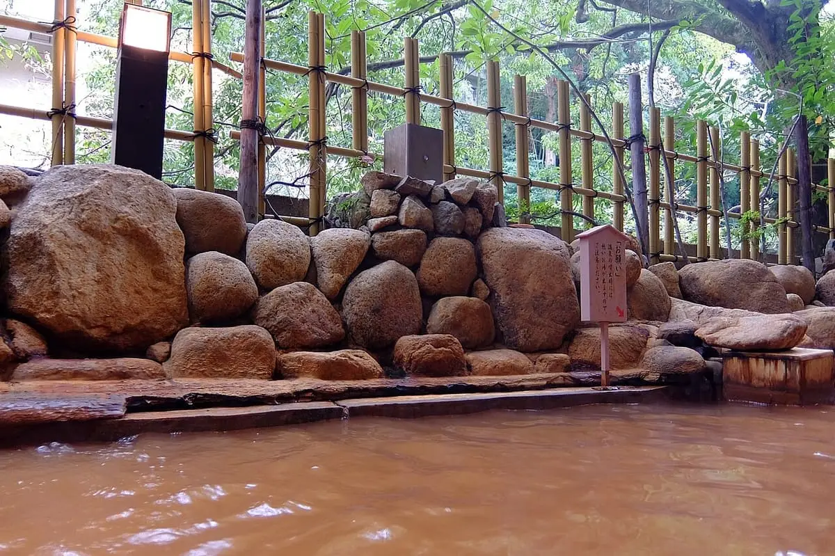 Rusty brown kinsen hot spring water in a rock lined pool at an Arima Onsen inn
