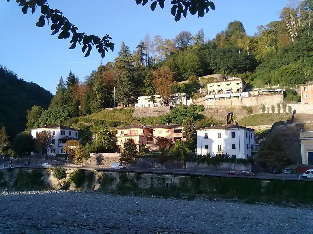 Wooded hillside and buildings above the stony riverbed at Bagni di Lucca