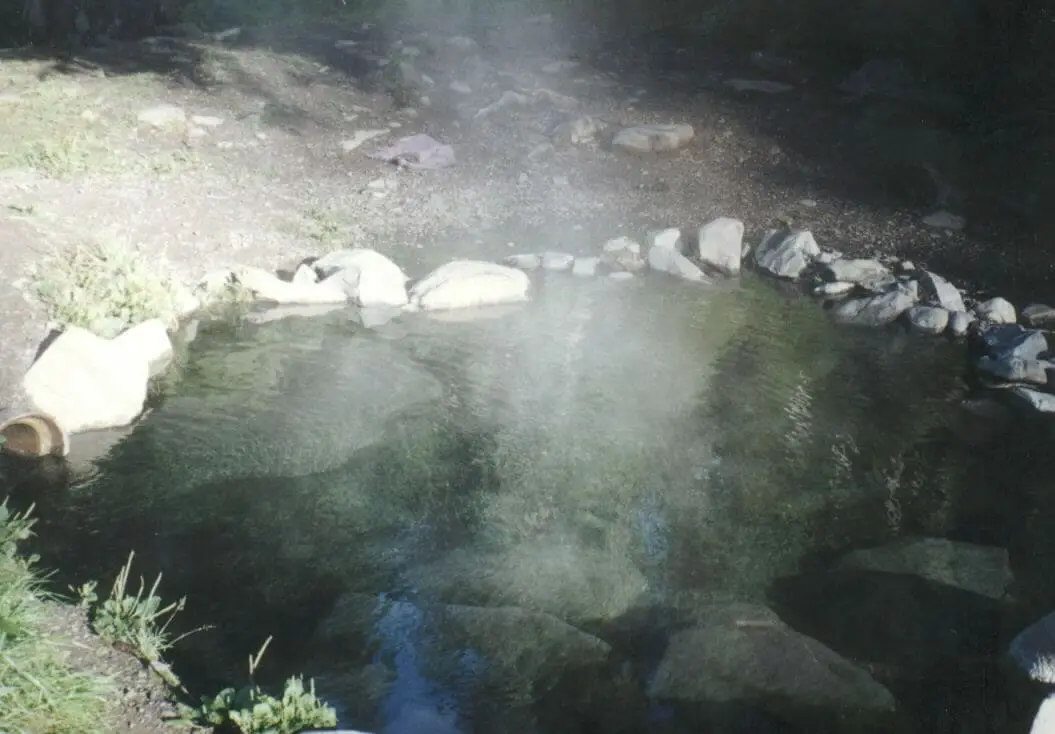 Steam rising from a clear rock ringed soaking pool at Olympic Hot Springs