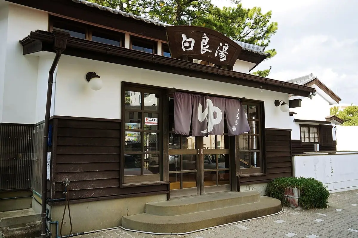 White walled Shirarayu public bathhouse with wooden front and noren in Shirahama