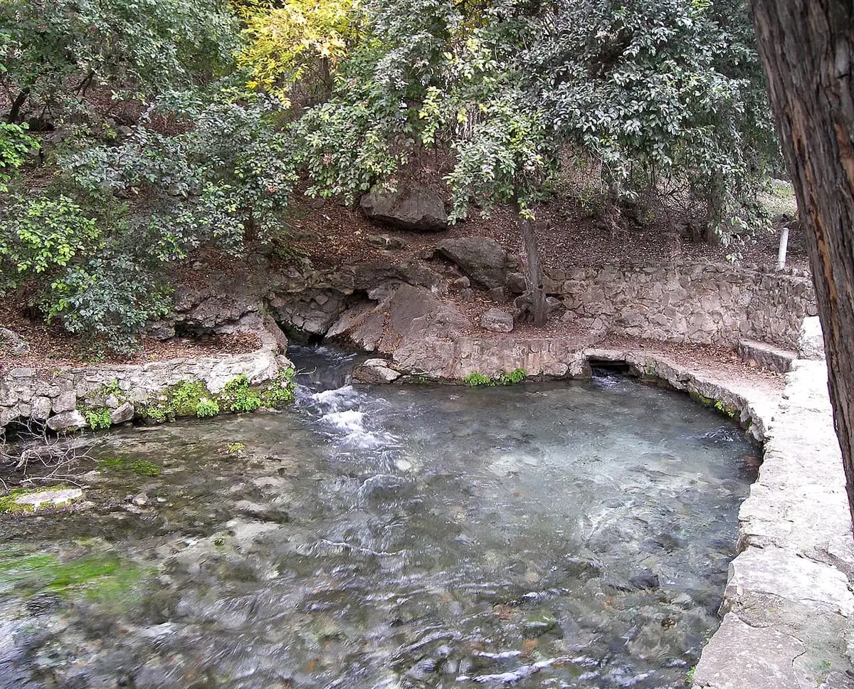 Comal Springs bubbling into a rocky pool beside a stone wall in Landa Park, New Braunfels