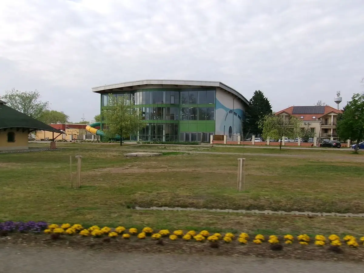 Modern glass winter bath building of the Cserkeszőlő spa beyond a lawn and flower bed