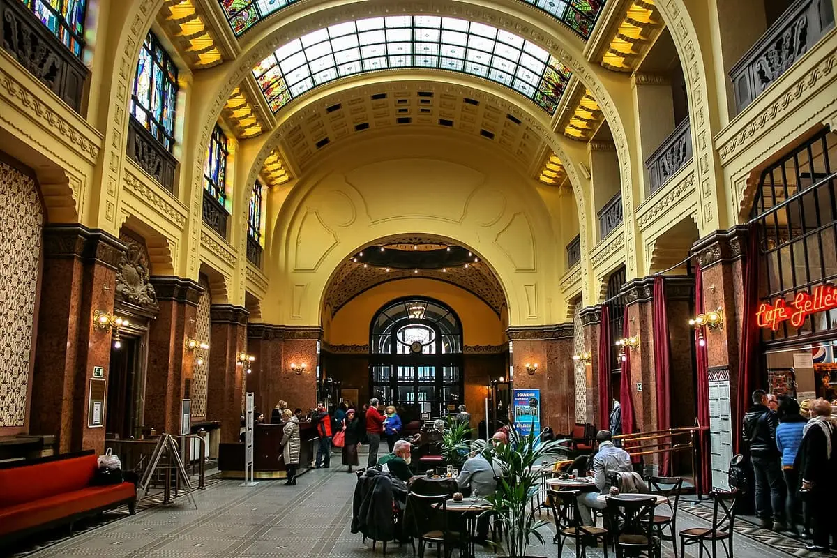 Grand vaulted entrance hall of the Gellért Bath with a glass roof and café tables