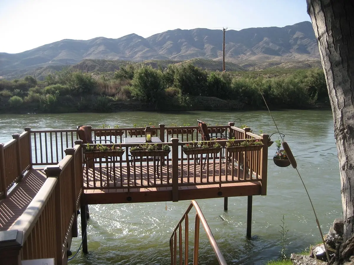 Wooden deck with chairs and flower boxes built out over the Rio Grande at Riverbend Hot Springs