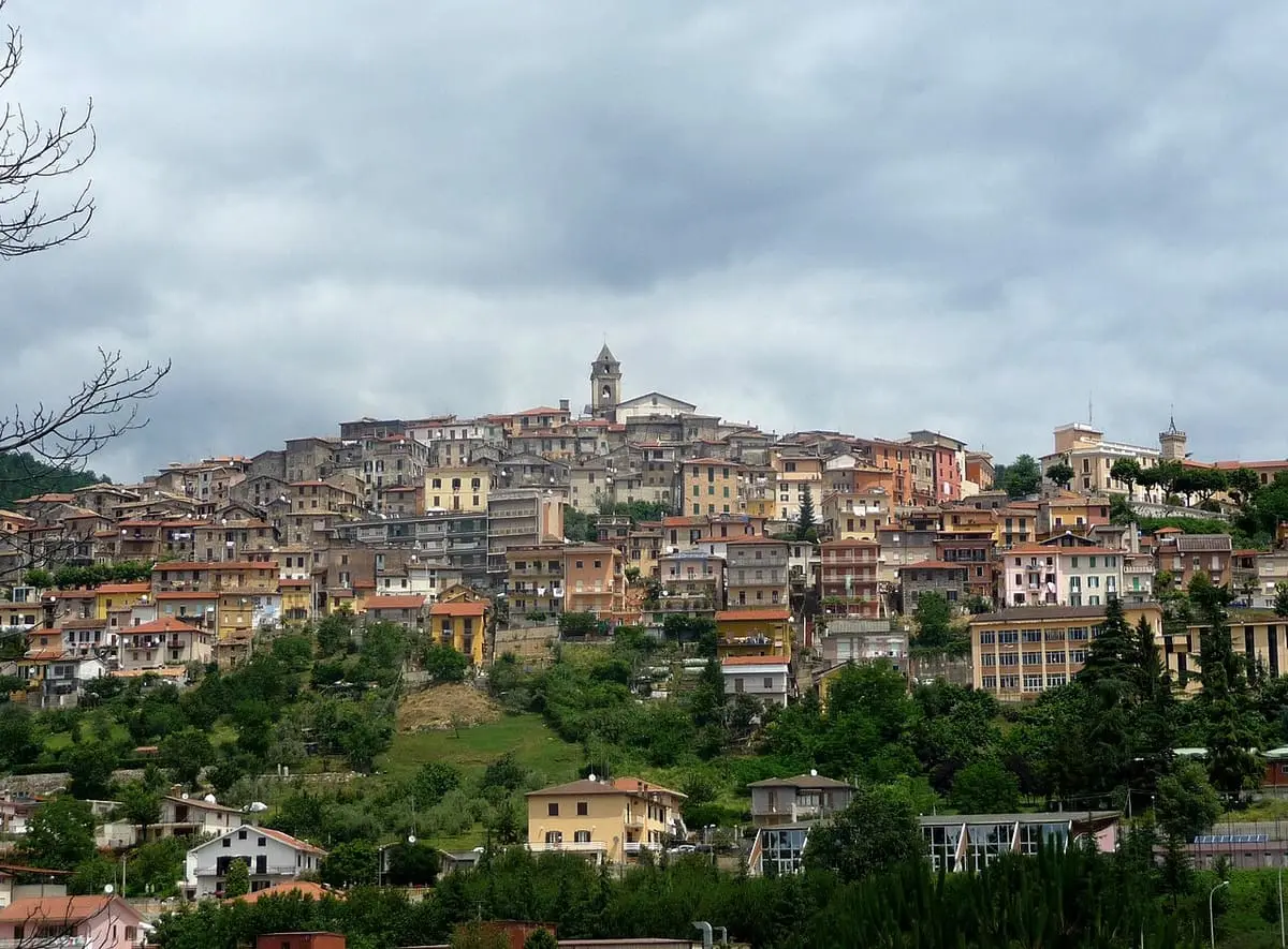Hilltop old town of Fiuggi above green trees under a cloudy sky