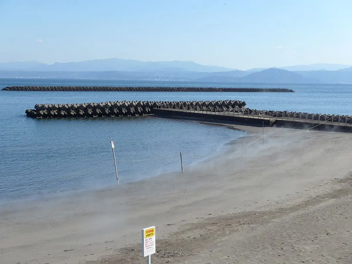 Hot sand bath beach at Ibusuki with breakwaters and distant mountains across the bay