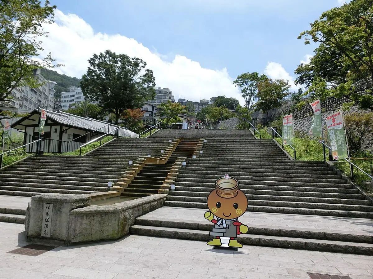 Wide stone stairway of the Ikaho Onsen stone steps street framed by trees and blue sky