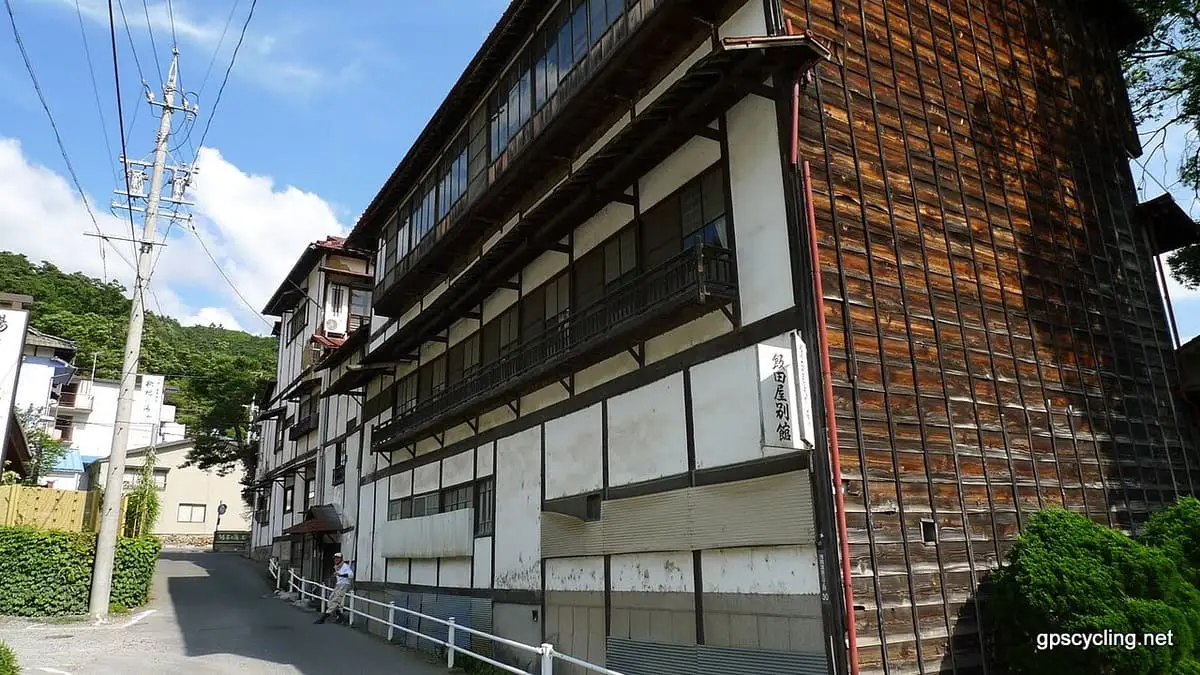Old wooden inn building with tall windows along a quiet street in Asama Onsen