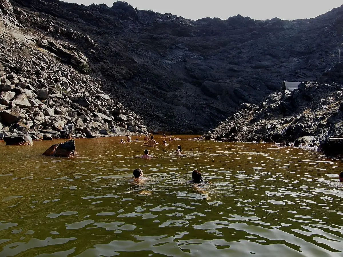 Iron stained warm water filling the narrow volcanic bay at Palea Kameni hot springs