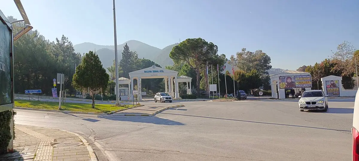 Road leading to the entrance gates of the Balçova Termal Otel with hills behind