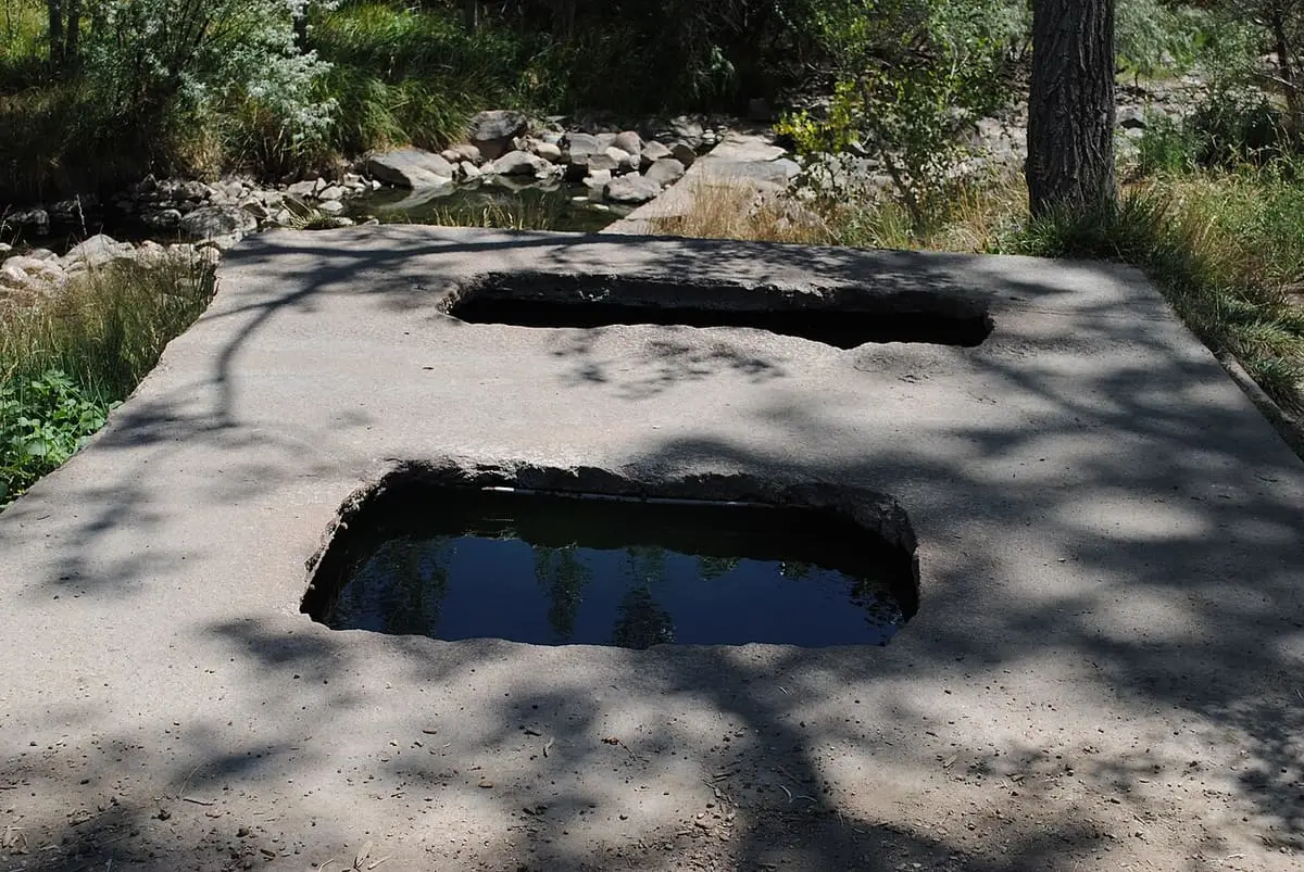 Two rectangular soaking tubs cut into a shaded concrete slab at Montezuma Hot Springs