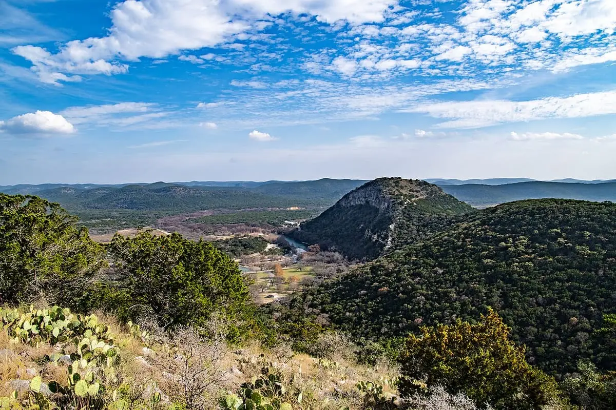 Old Baldy hill and wooded Frio River valley under a blue sky at Garner State Park