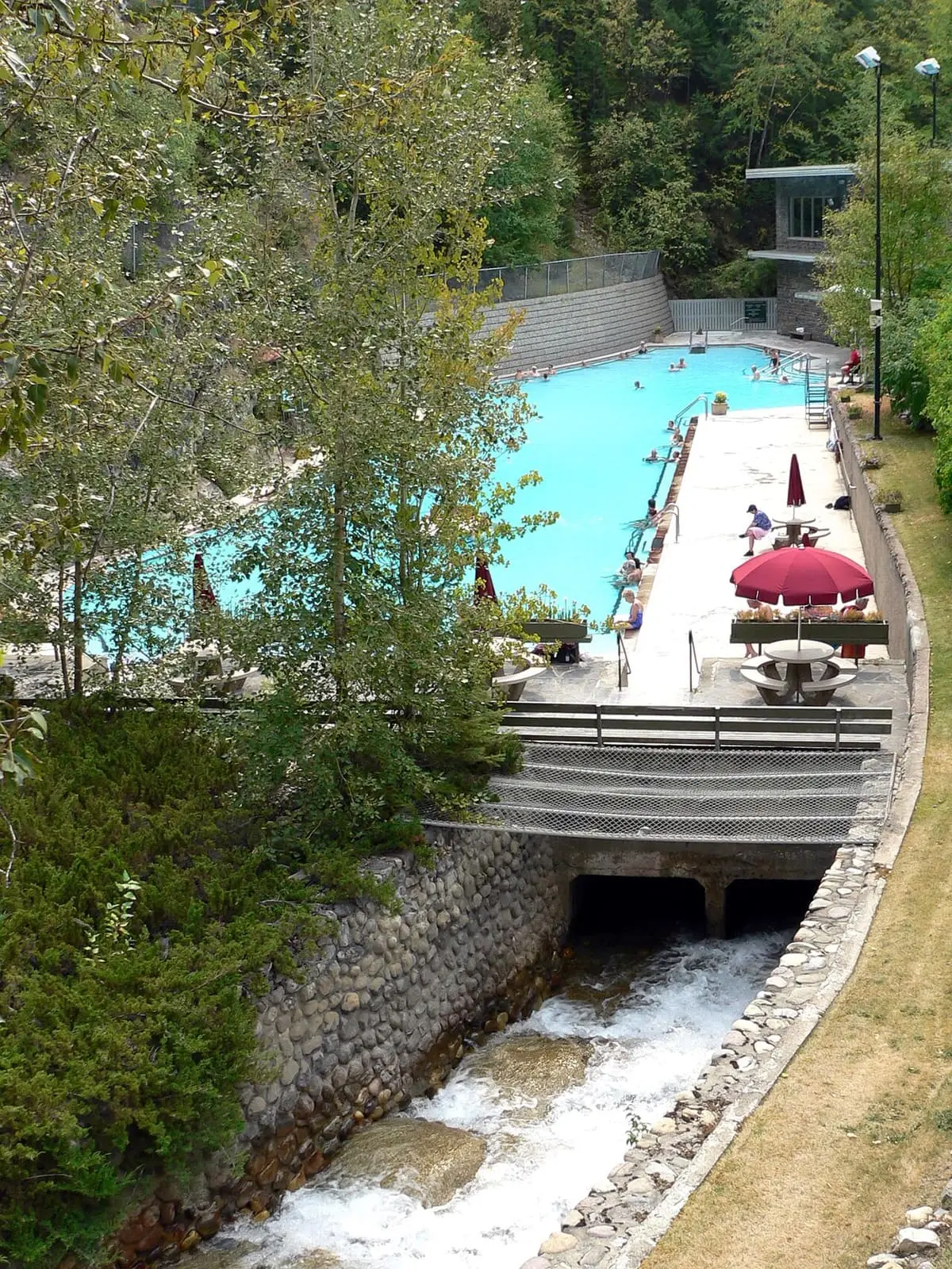 Radium Hot Springs pools seen from above with a creek running below the deck