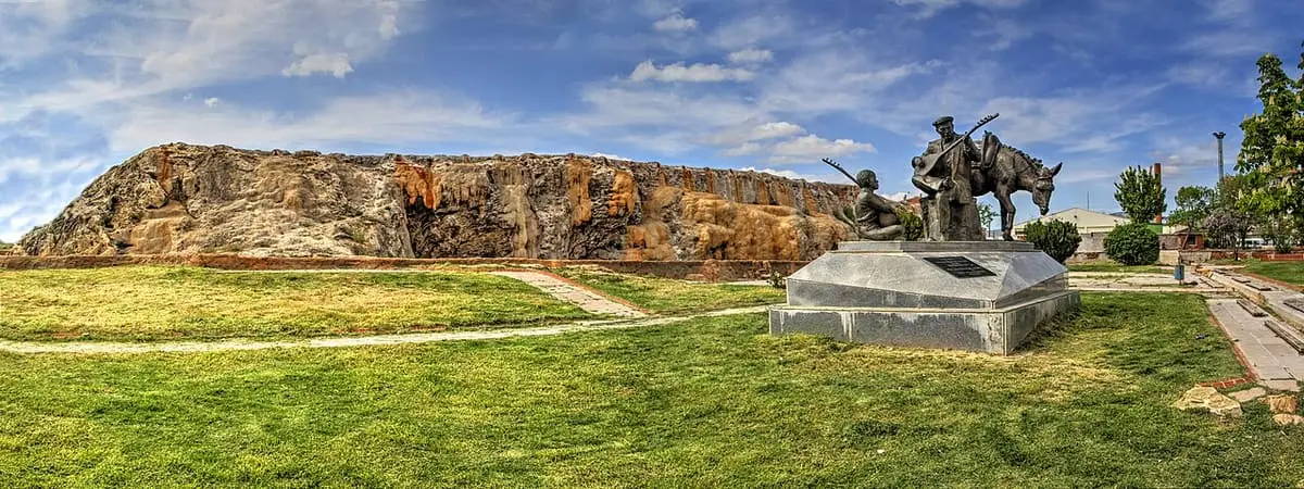 Long rock outcrop in the Terme area of Kırşehir with a bronze statue on a lawn