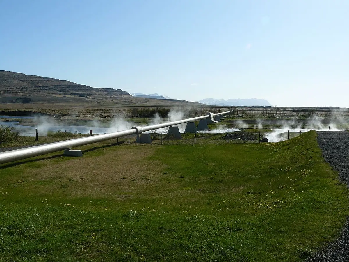 Hot water pipeline running from the steaming Deildartunguhver spring area across green grass