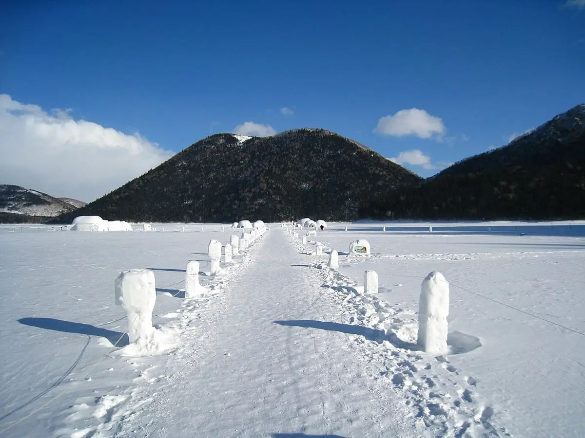 Snow path lined with ice posts leading across the frozen lake at Shikaribetsu Kotan