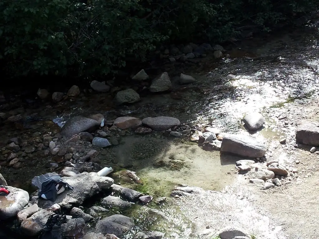 Shallow rock lined pool at the edge of Trail Creek in dappled sunlight