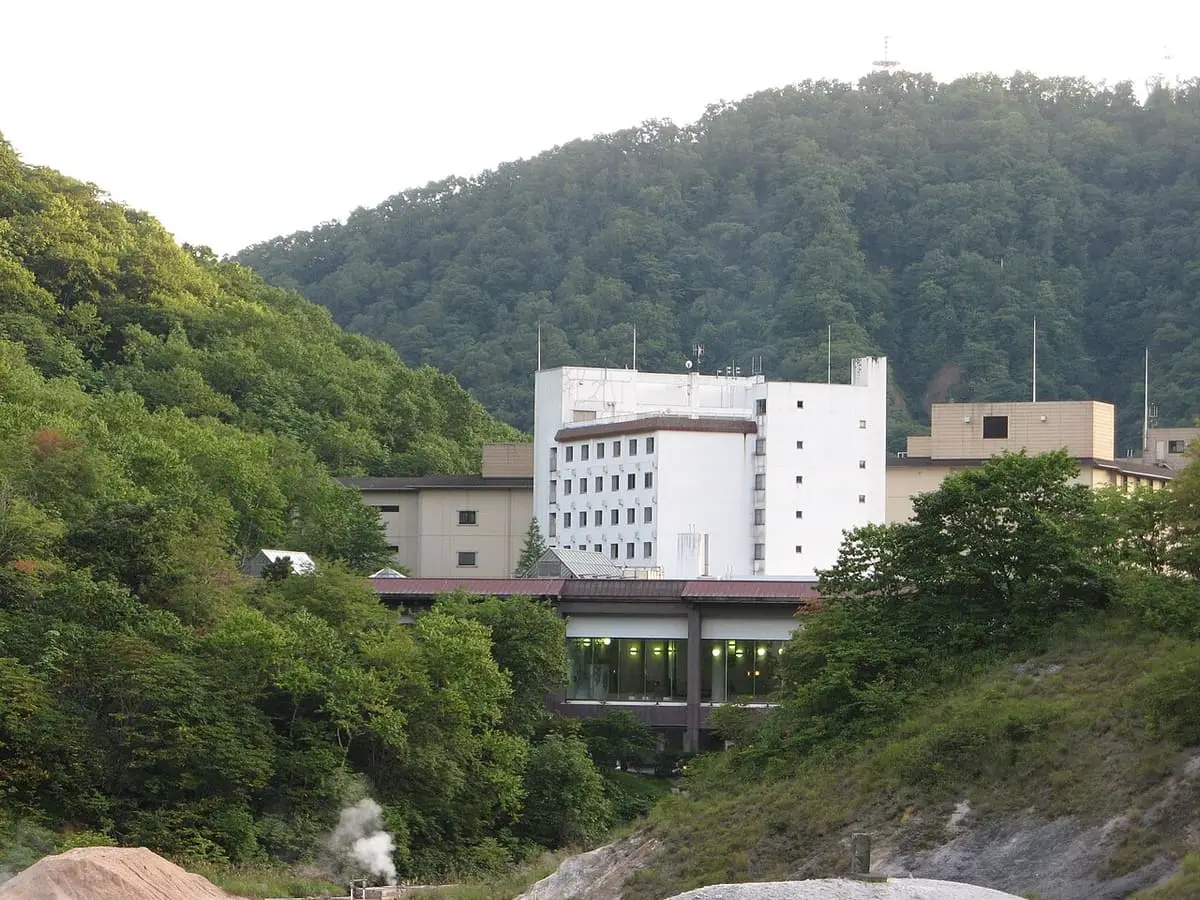 White Dai-ichi Takimotokan hotel buildings set below forested hills in Noboribetsu Onsen
