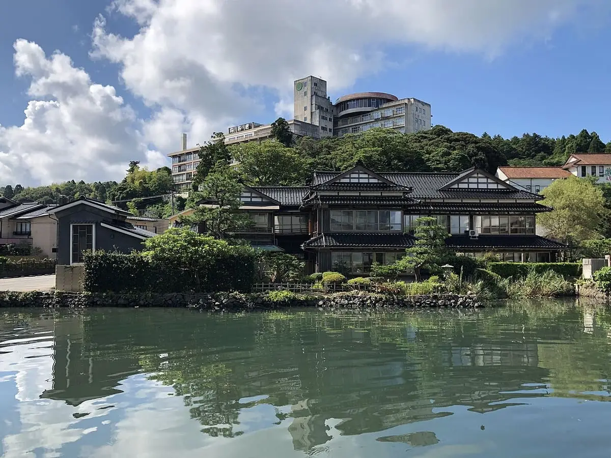 Traditional inn buildings and pine trees along the waterfront at Wakura Onsen