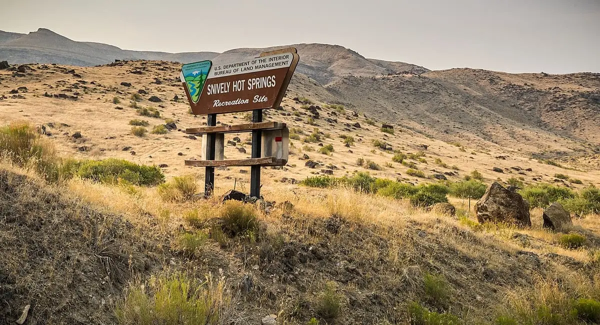 Brown BLM sign for Snively Hot Springs on a dry sagebrush hillside in the Owyhee canyon