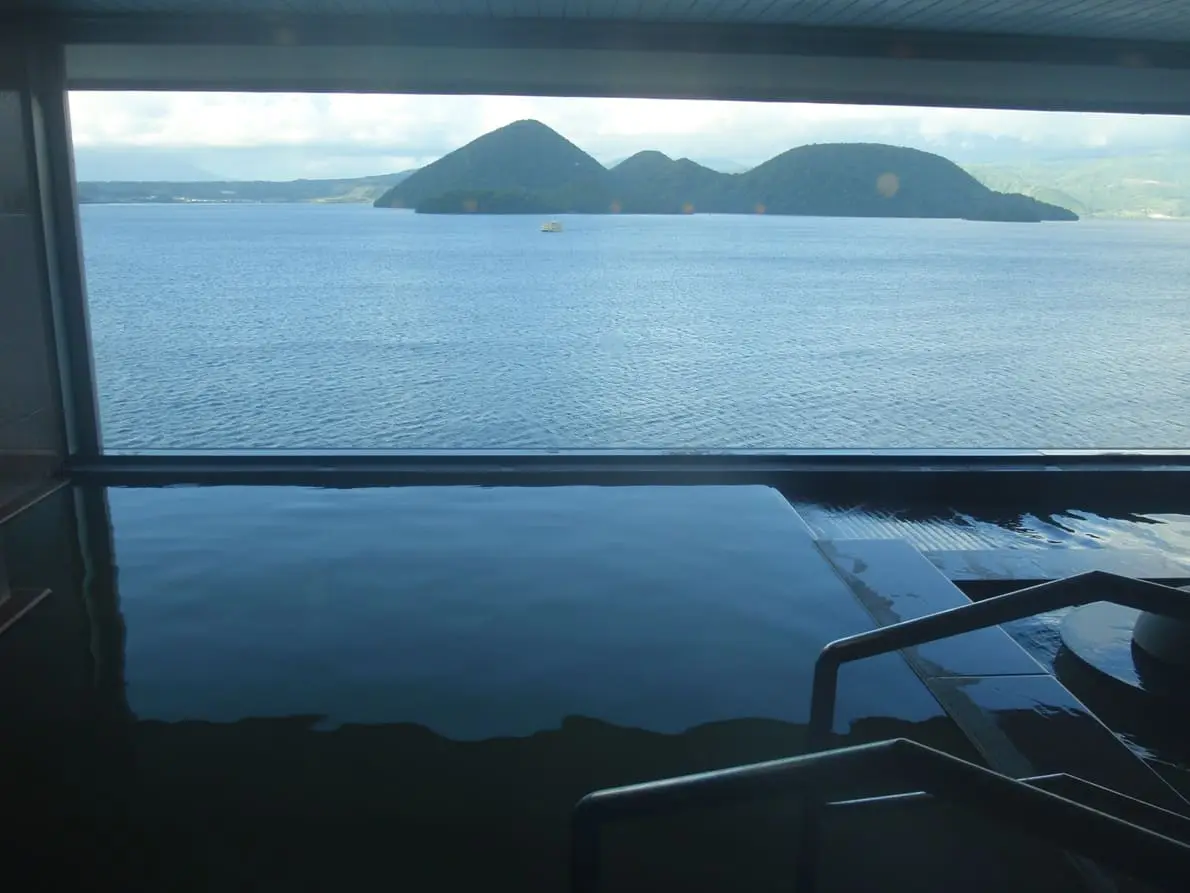 Indoor hot spring bath at Kohankaku with a window view over Lake Toya and its islands