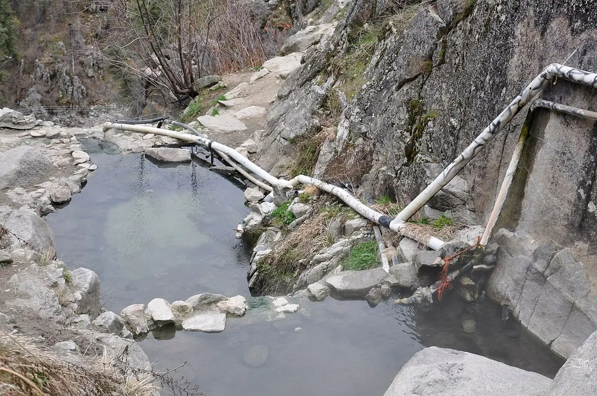 Stone walled pools and log piping on the steep slope at Skinny Dipper Hot Springs