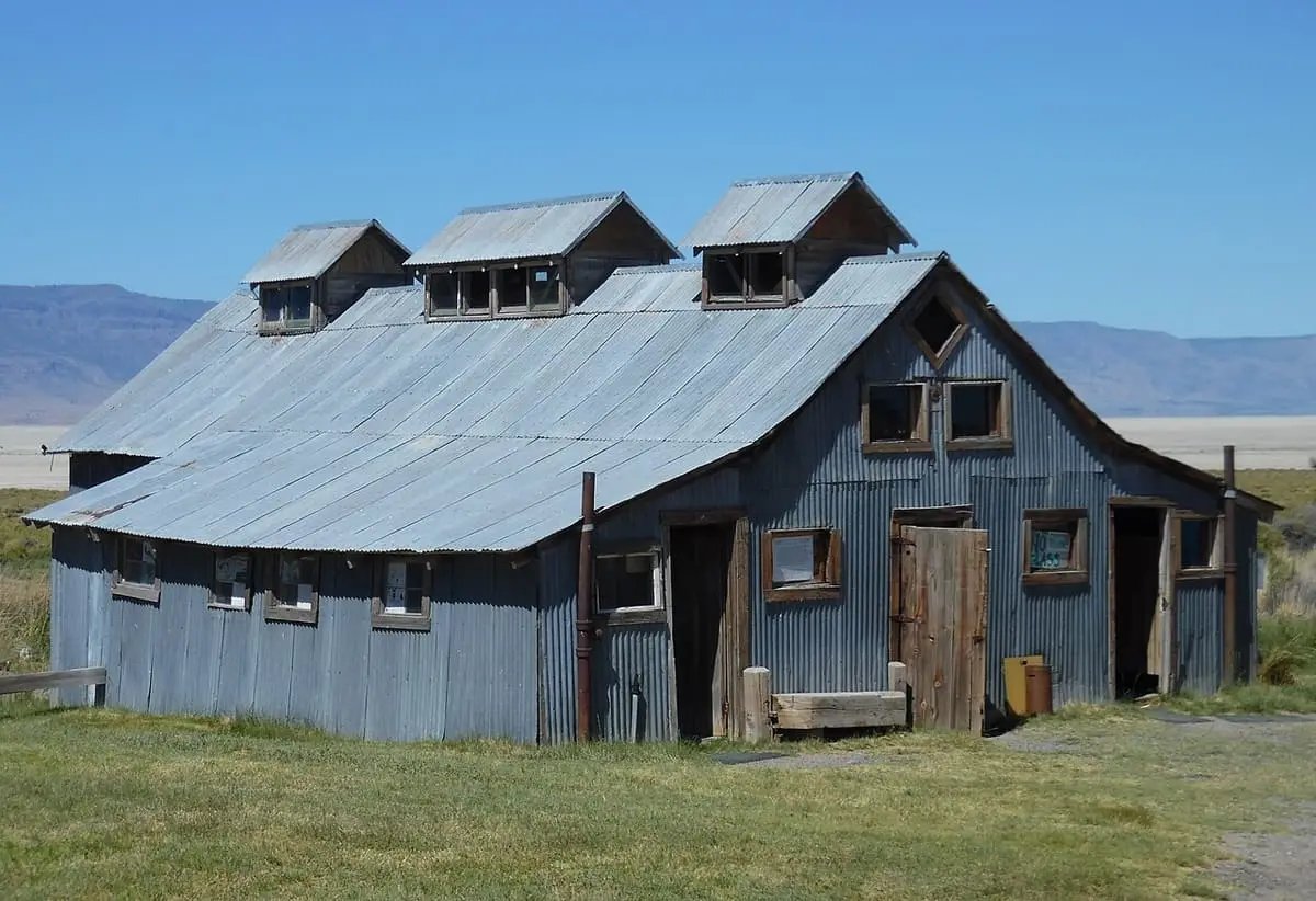 Weathered gray bathhouse with roof vents at Summer Lake Hot Springs under a blue sky