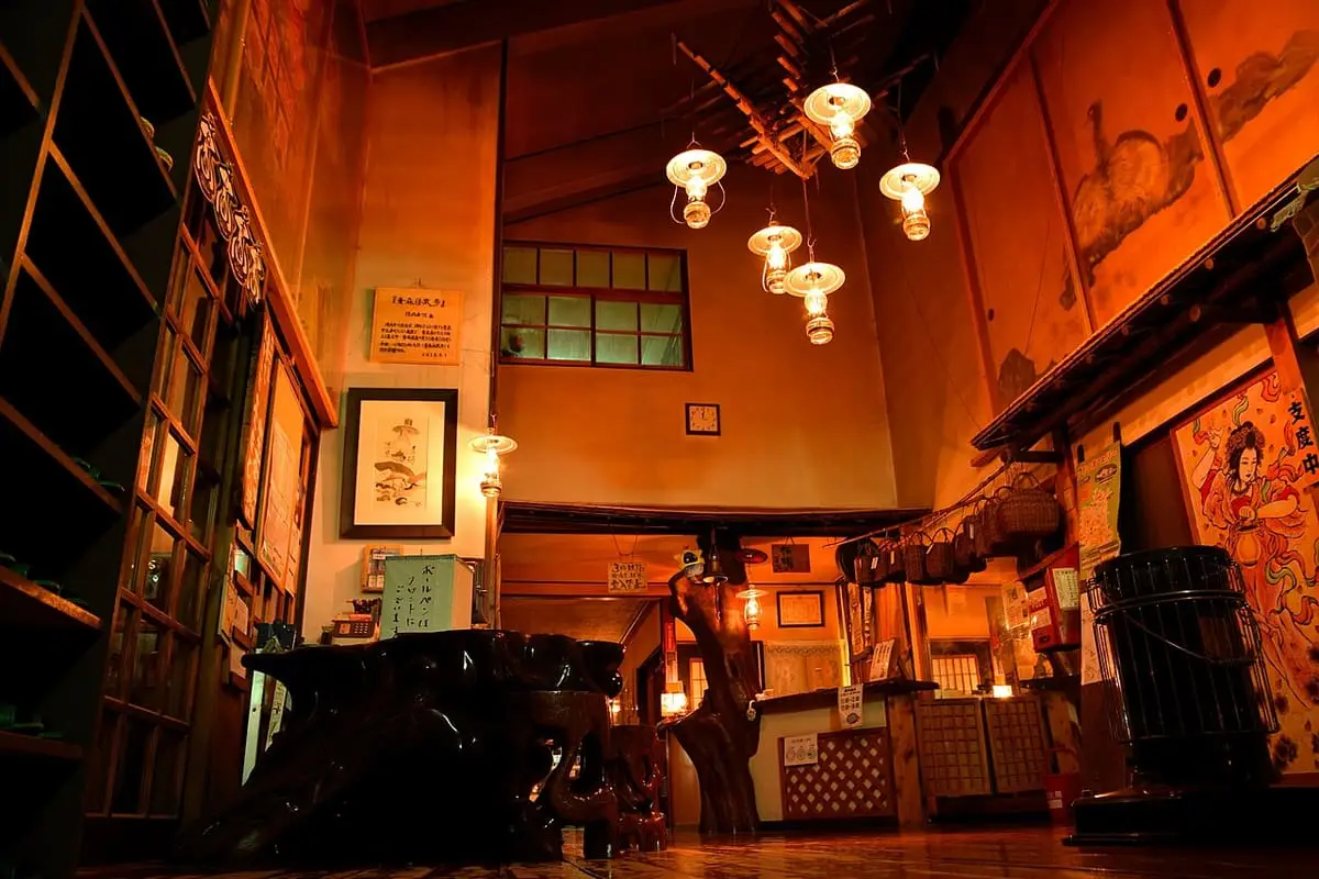 Lamp lit wooden lobby with hanging oil lamps at Lamp no Yado Aoni Onsen