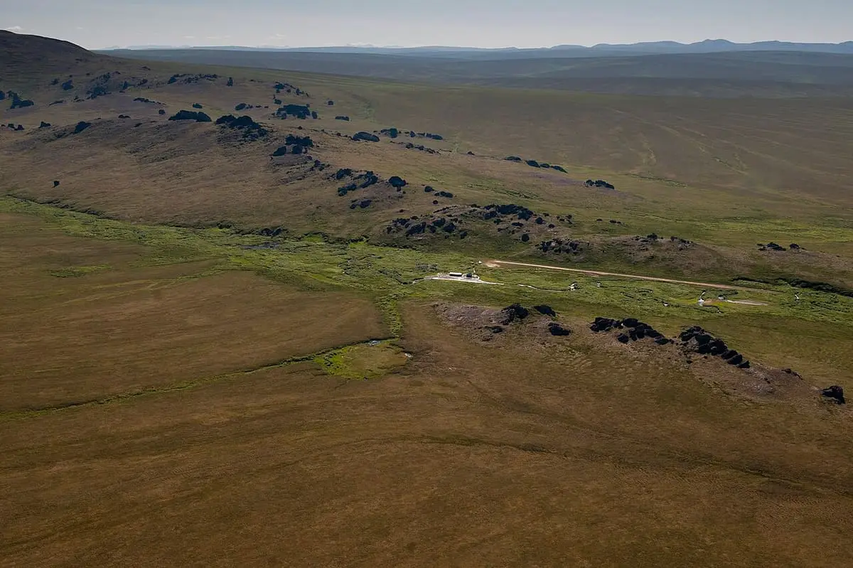 Aerial view of the Serpentine Hot Springs buildings in a tundra valley dotted with granite tors