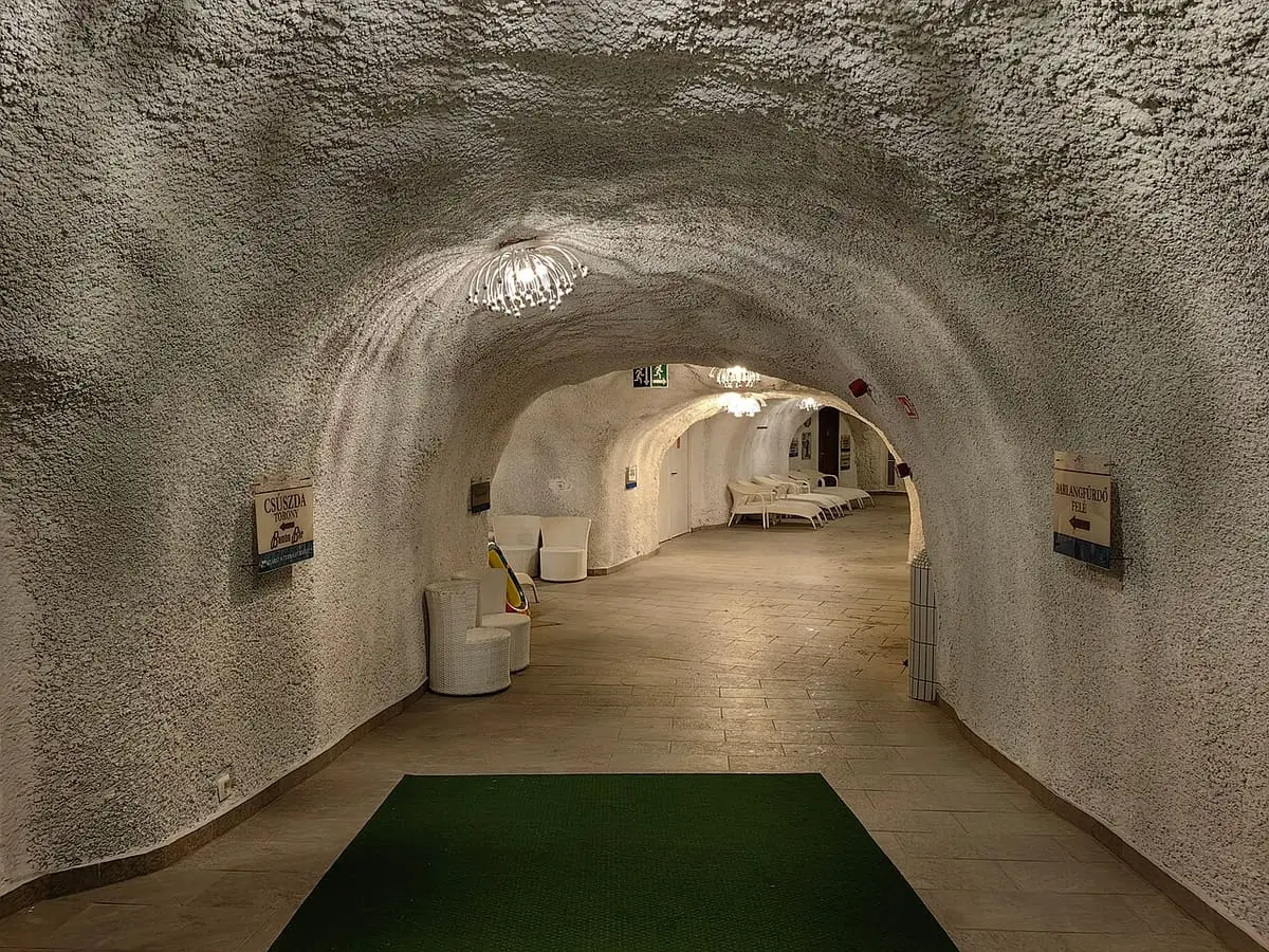 Arched artificial rock corridor lined with loungers inside the Cascade cave bath