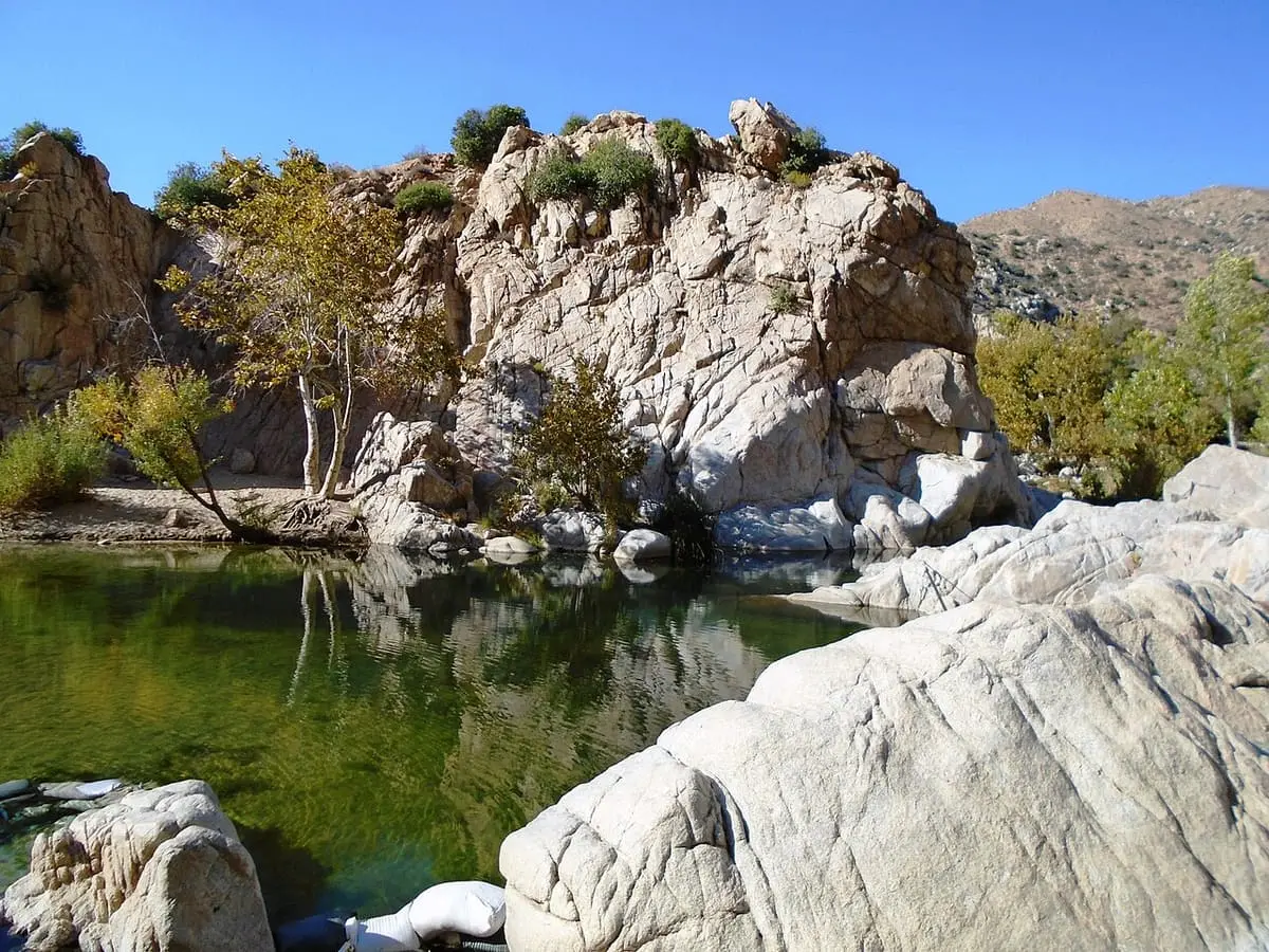 Green pool of Deep Creek reflecting a granite outcrop and trees near Deep Creek Hot Springs