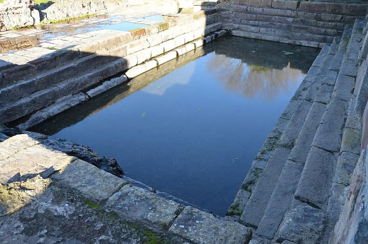 Ancient rectangular stone basin holding still water in the Roman baths of Fordongianus