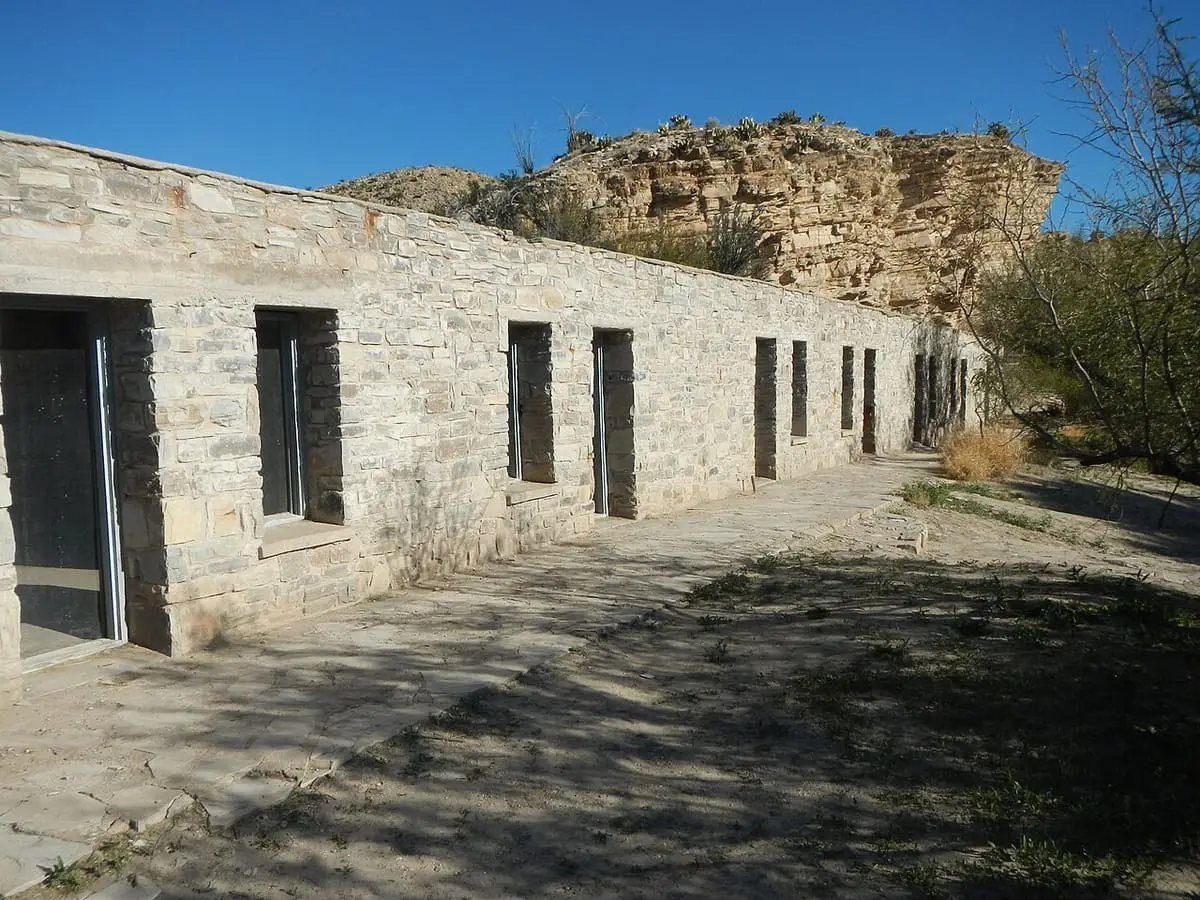 Long row of historic stone guest rooms at the Hot Springs site below a limestone bluff