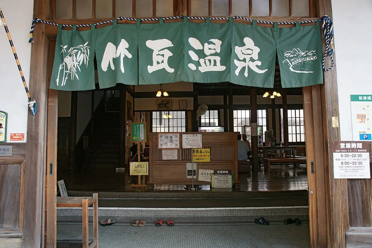 Green noren and wooden reception hall inside the entrance of Takegawara Onsen