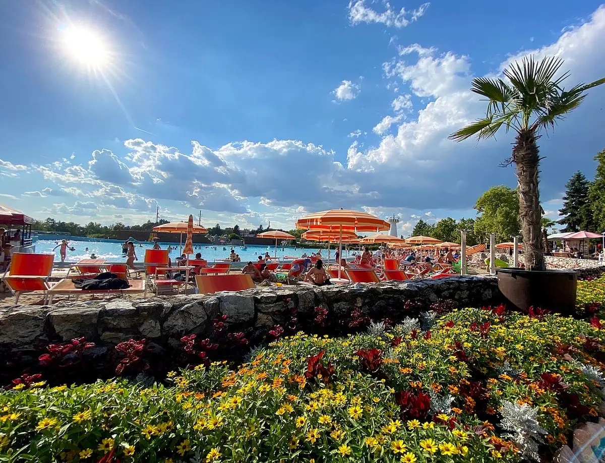 Flower beds and a palm overlooking the sandy beach area of Hungarospa Hajdúszoboszló