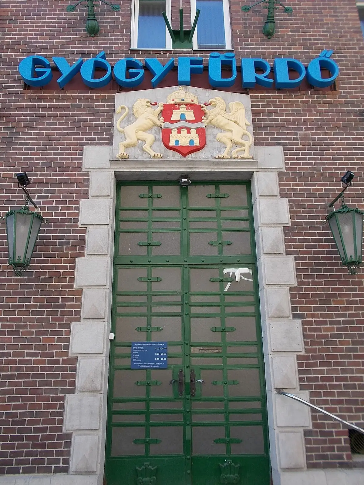 Green iron entrance doors and coat of arms under the Gyógyfürdő sign at Dandár Bath