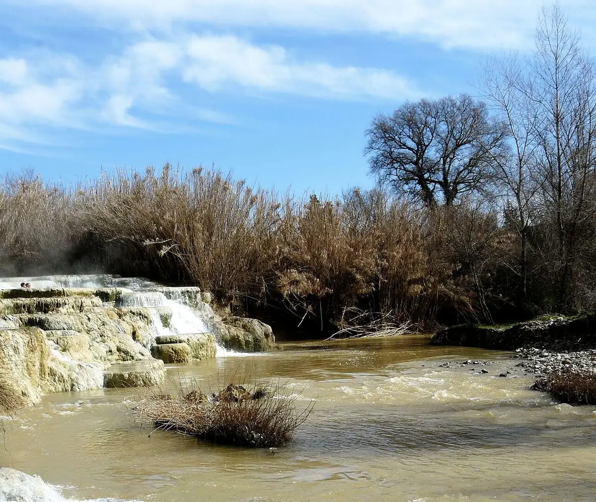 Steaming thermal stream below a small travertine cascade at Cascate del Mulino in Saturnia