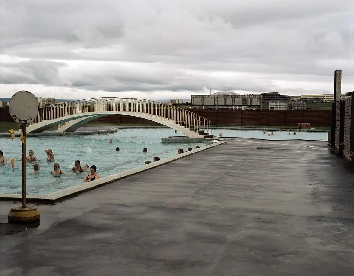 Outdoor pool deck at Laugardalslaug with a small arched bridge over the water
