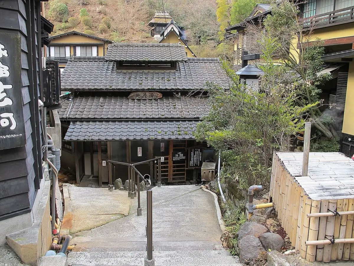 Traditional tiled roof inn and stone steps among trees at Kurokawa Onsen