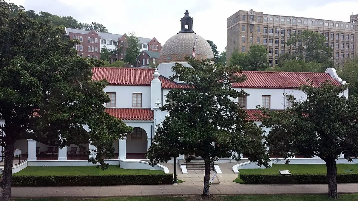 Quapaw Bathhouse with red tile roof and central dome seen across Central Avenue behind trees