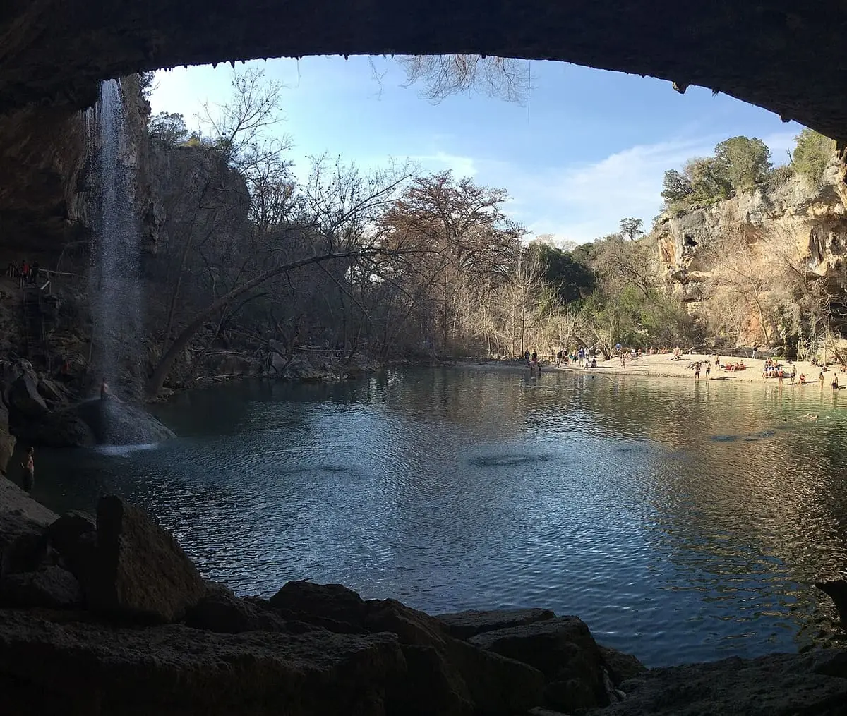 View from beneath the rock overhang across Hamilton Pool toward wooded cliffs