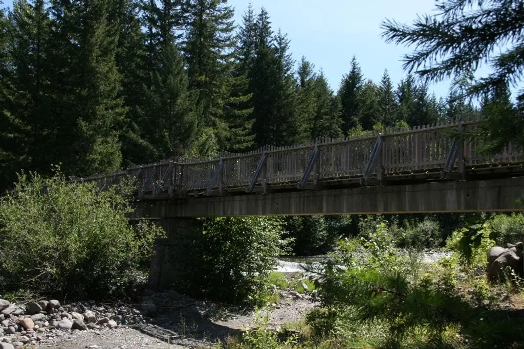Wooden footbridge spanning the rocky Breitenbush River in dense forest