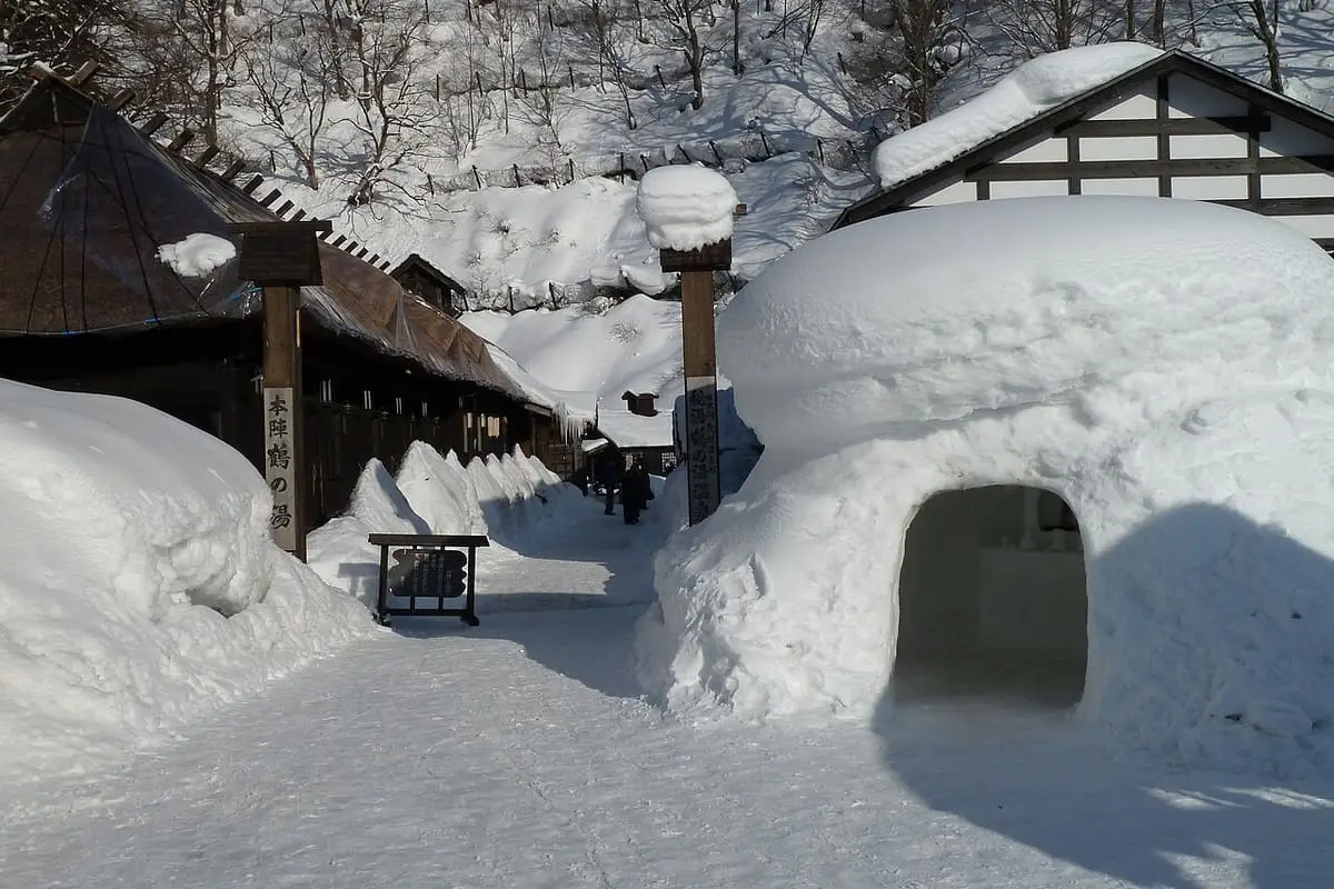 Deep snow and a snow hut along the lane between Tsurunoyu Onsen buildings in winter