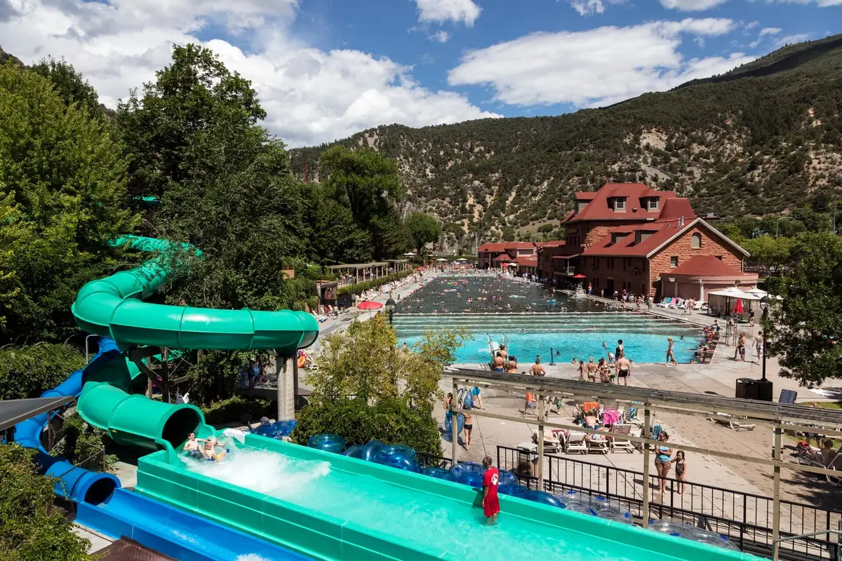 Twisting green water slides above the Glenwood Hot Springs pool area and red stone bathhouse