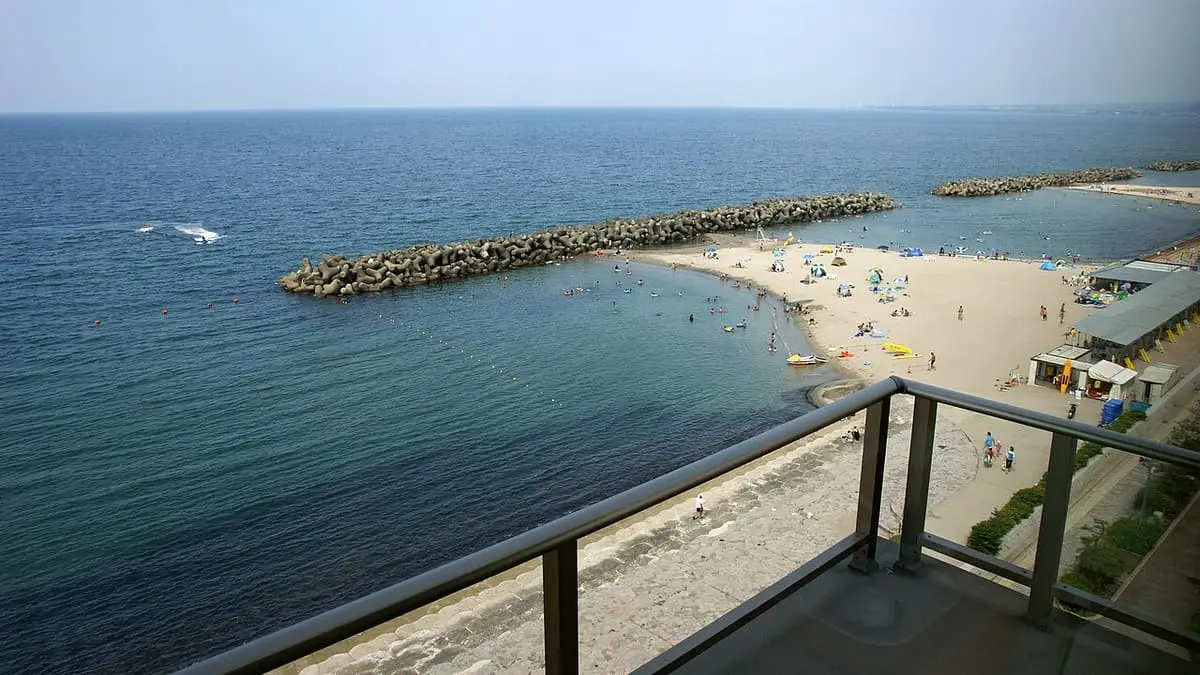 Kaike beach and breakwaters curving along the blue sea seen from a hotel balcony